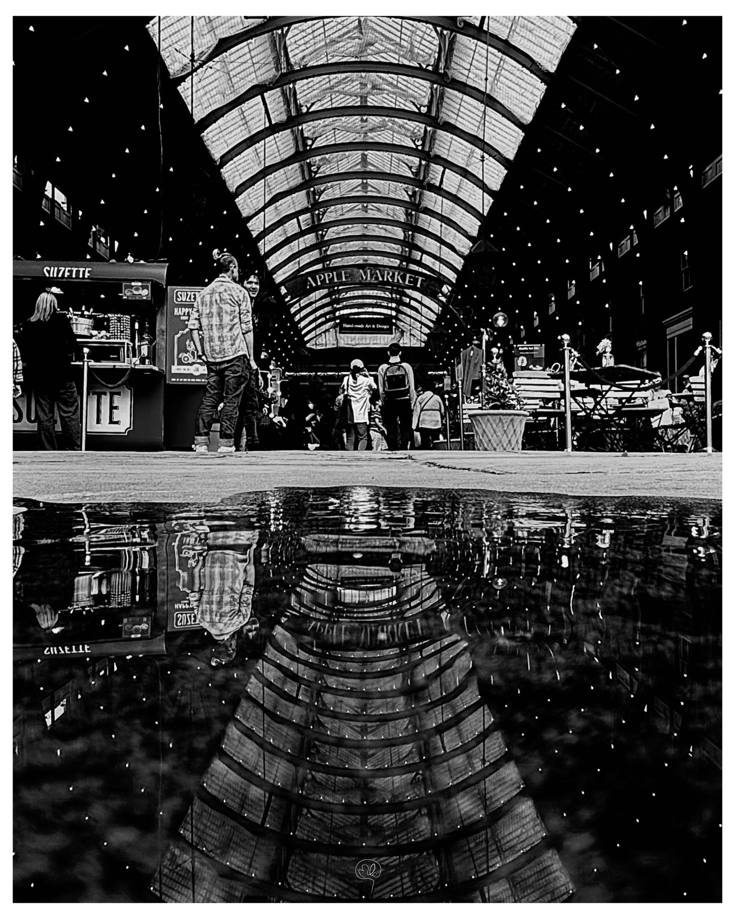 London's Apple Market and its visitors reflected in a puddle