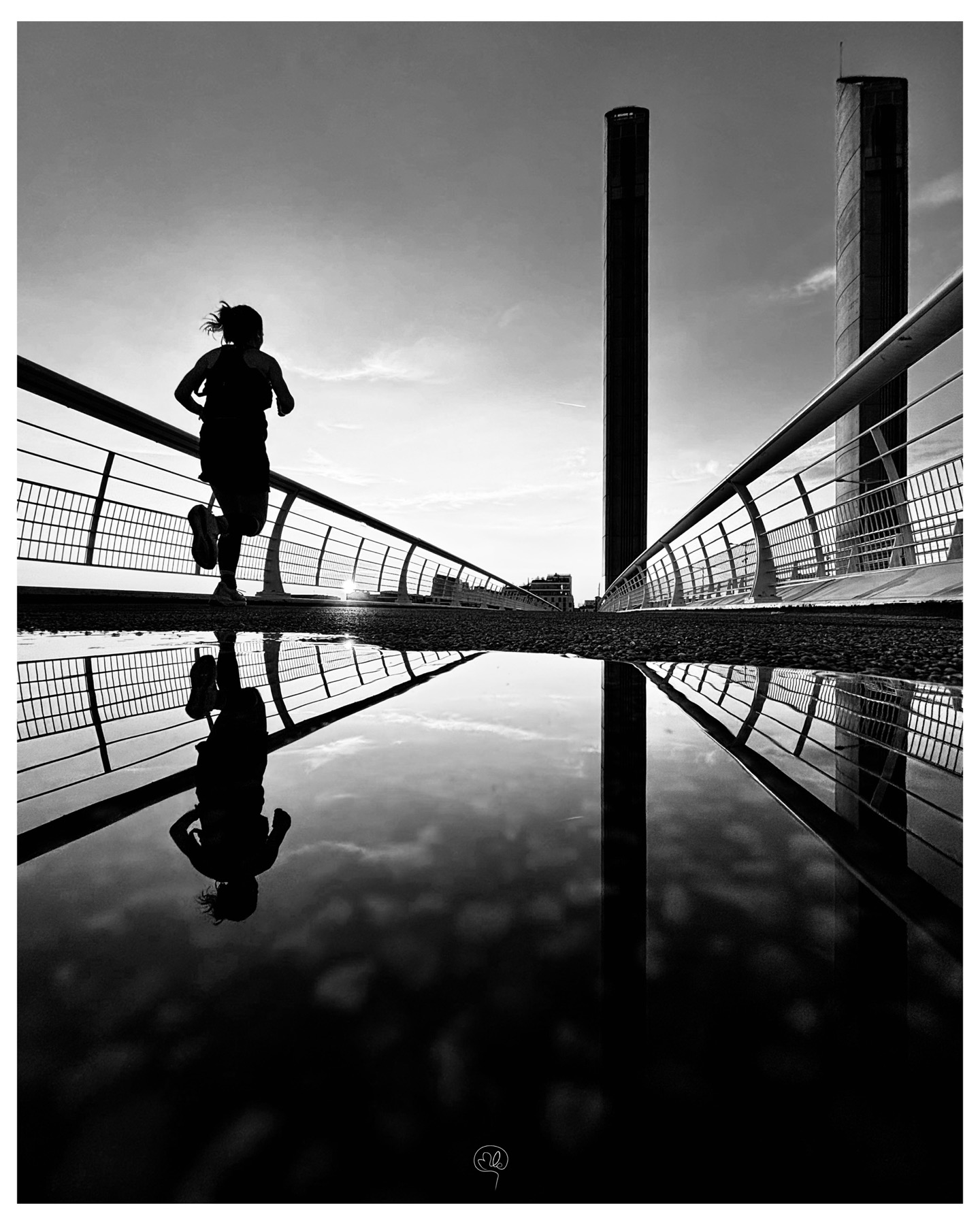 Silhouette of a runner on a footbridge and her reflection
