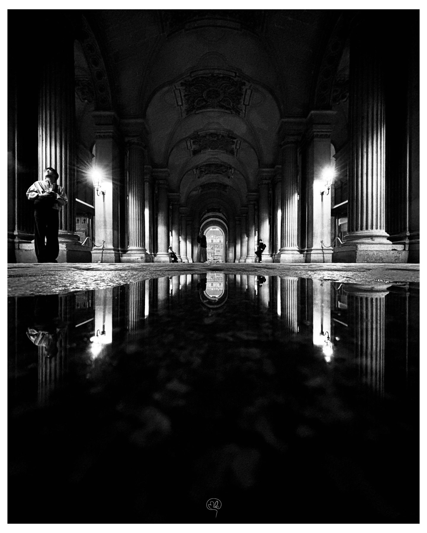 A long perspective of illuminated arcades reflected in a puddle