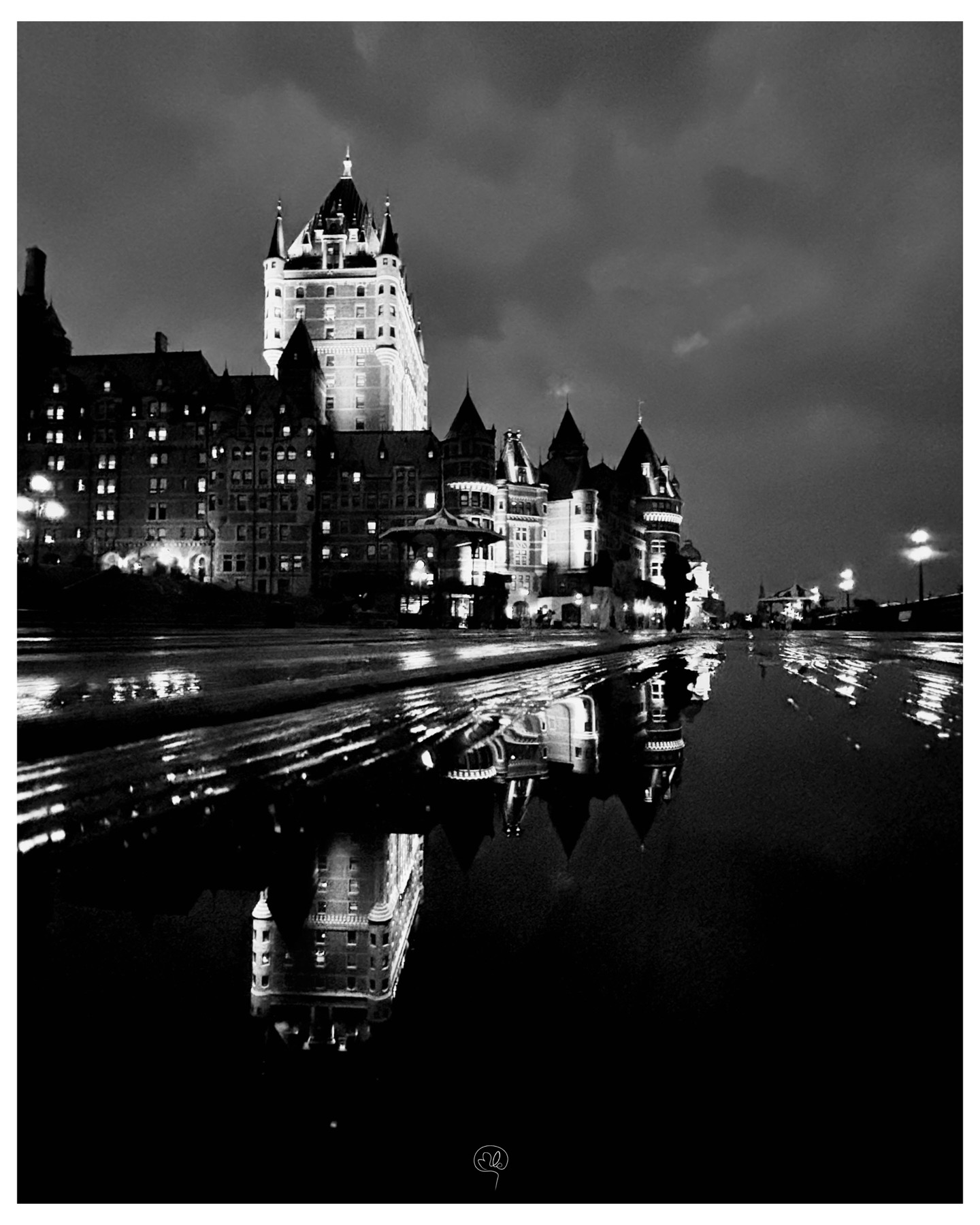 Illuminated Château Frontenac reflected on a wet roadway