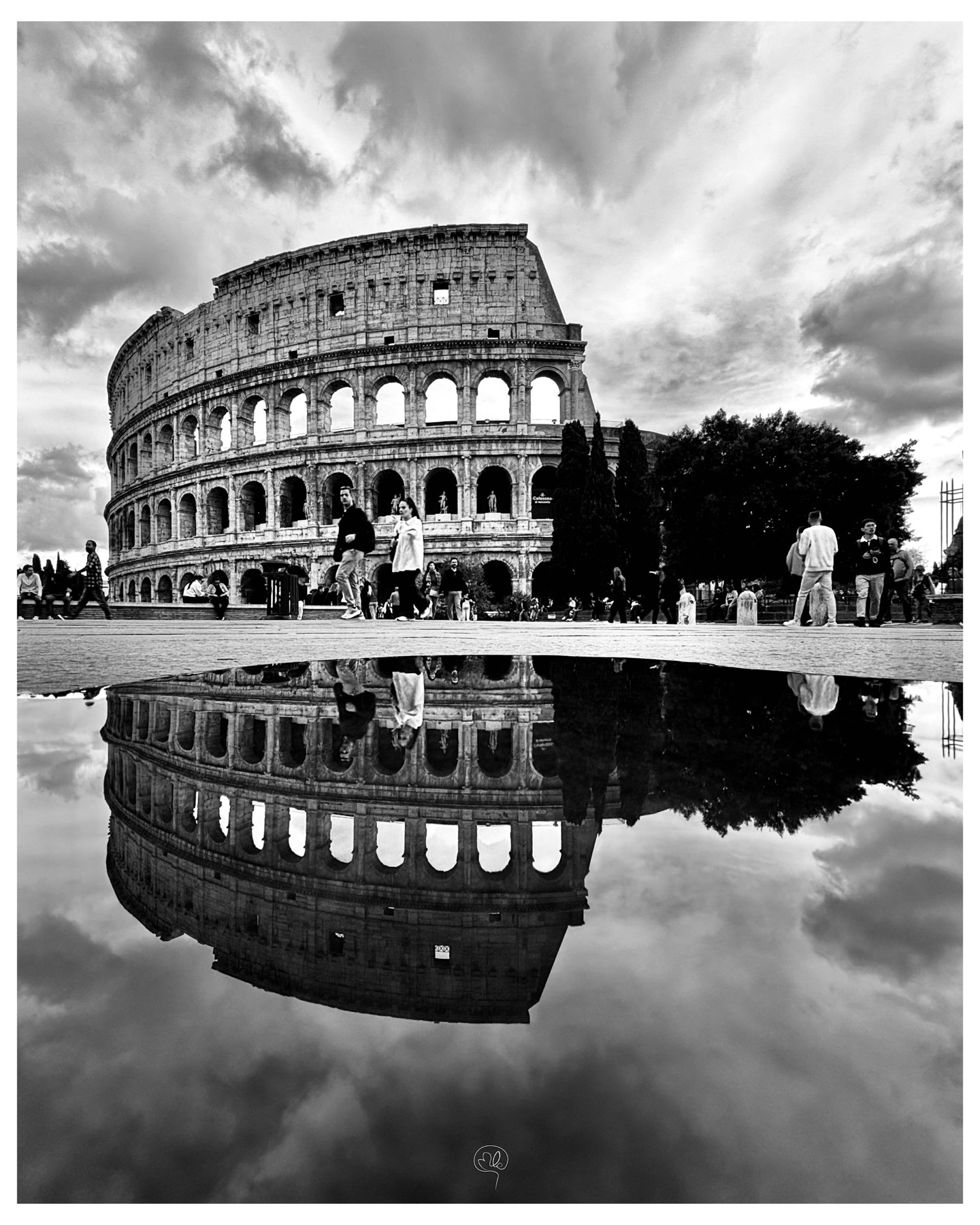The Colosseum in Rome and passers-by reflected in a puddle